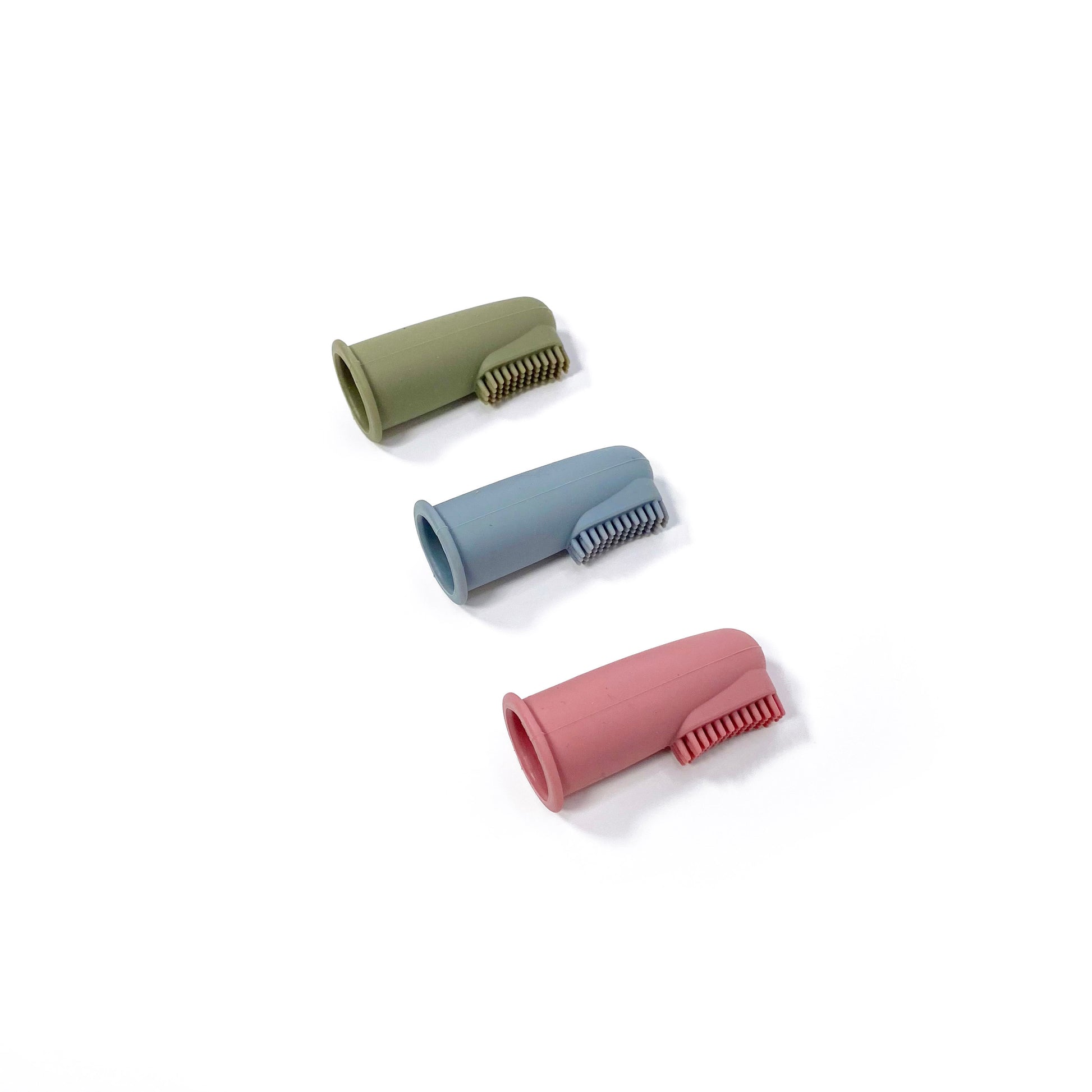 A set of silicone baby toothbrushes in colours khaki green, rose pink and ocean blue. Image shows the toothbrushes lying down, in a diagonal line.