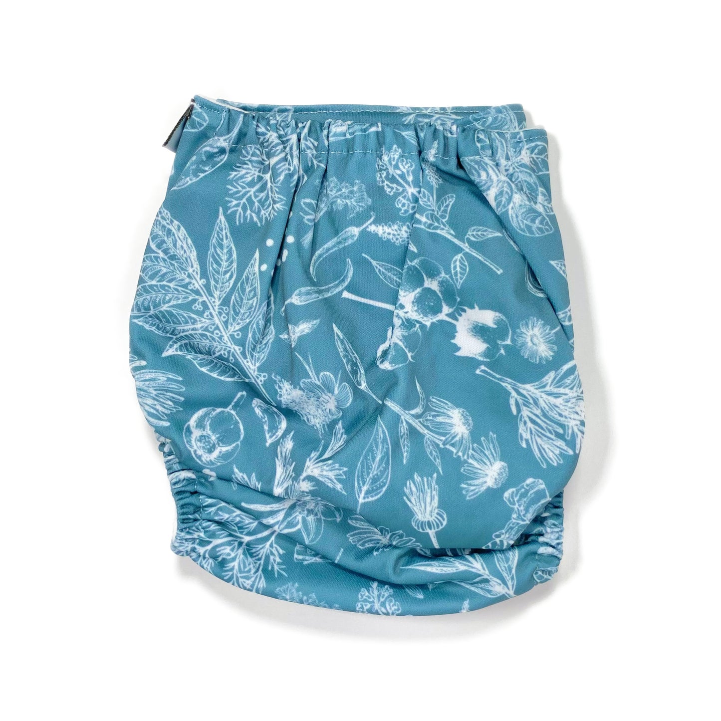 An adjustable reusable nappy for babies and toddlers, featuring a blue harvest design, with white images of various crops on a blue background. View shows the back of the nappy.