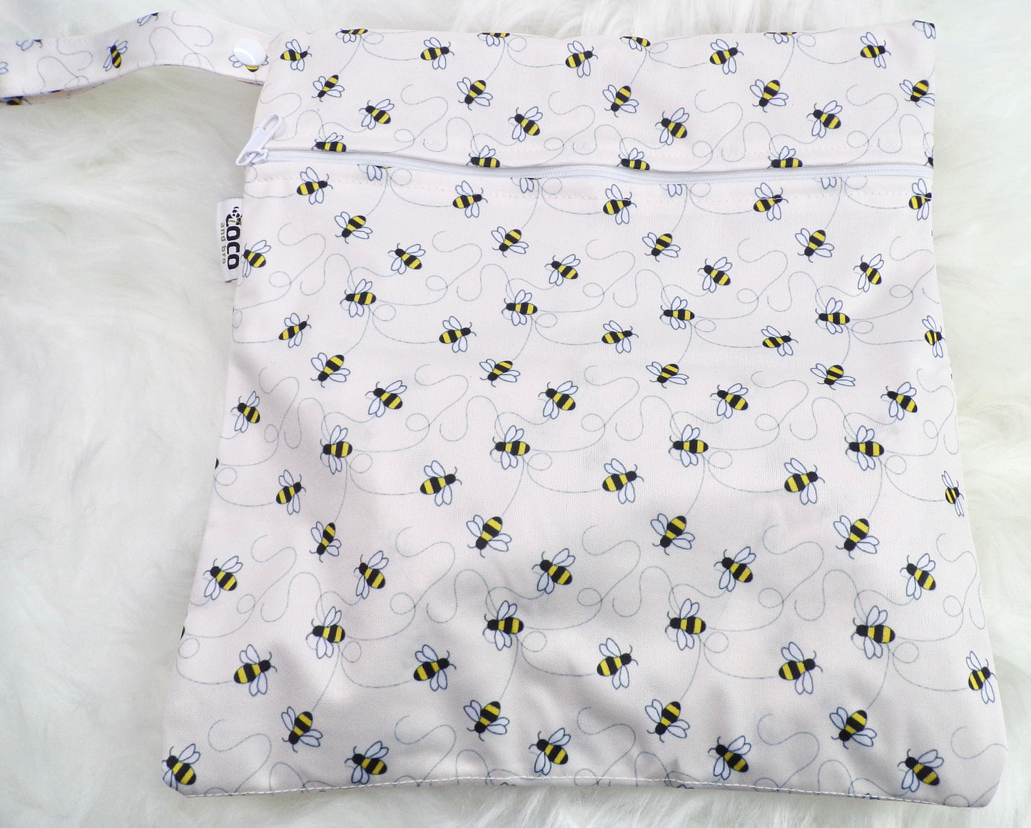 A set of three waterproof bags in an off-white bumble bee design, made from bamboo and in three different sizes. Each bag has a zipper closure. Image shown displays the largest bag with the two smaller bags contained within.