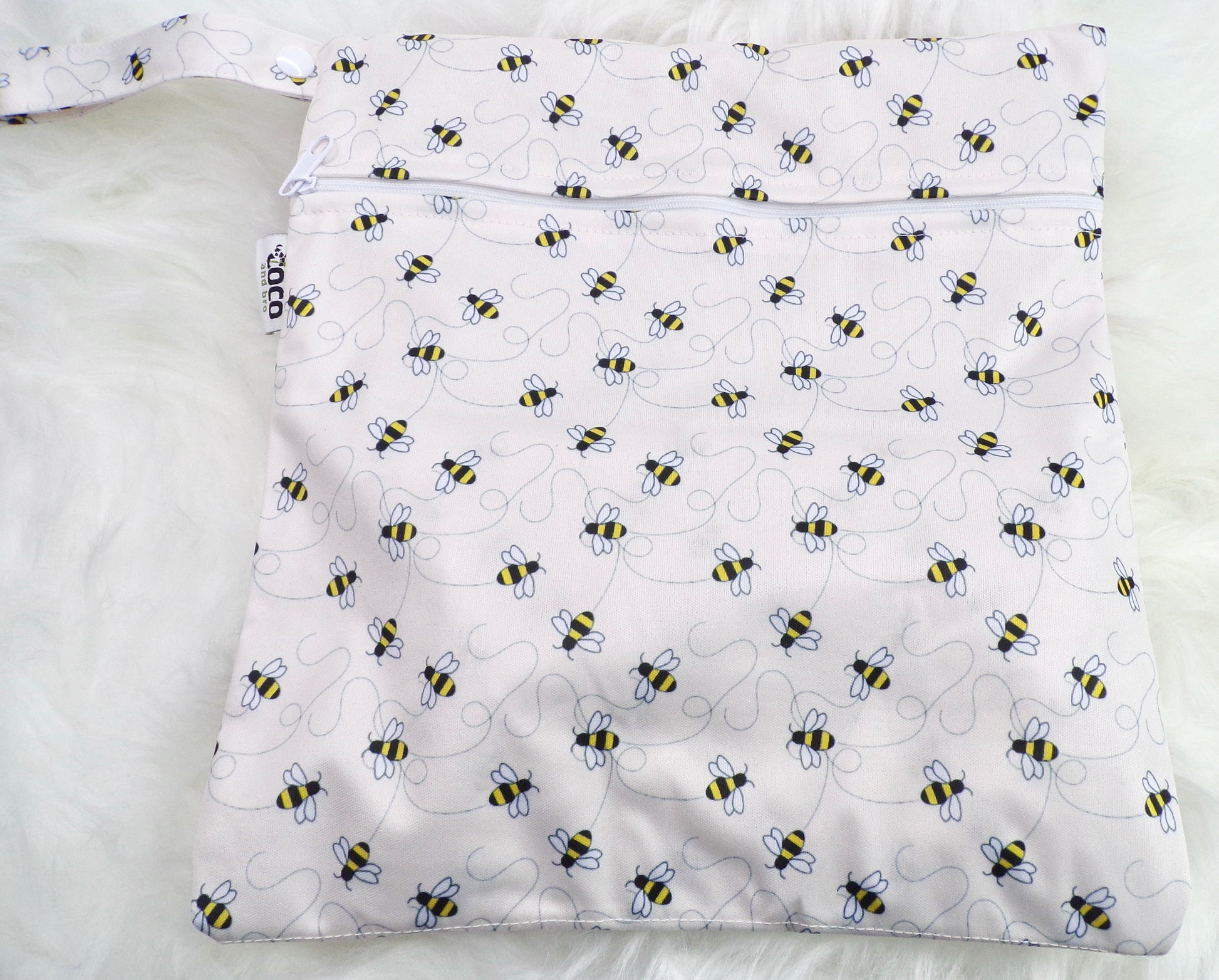 A set of three waterproof bags in an off-white bumble bee design, made from bamboo and in three different sizes. Each bag has a zipper closure. Image shown displays the largest bag with the two smaller bags contained within.