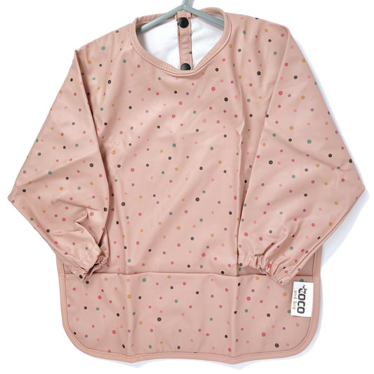 Long-sleeve kids apron in a rose pink and dotty design, showing front view.