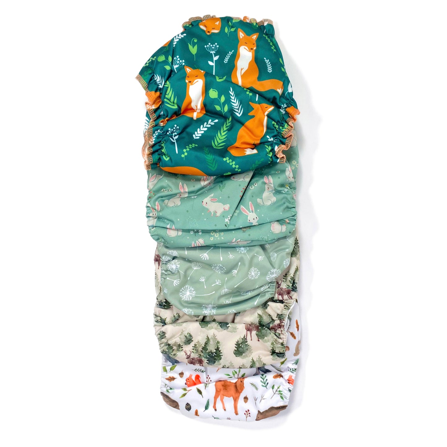 A set of five reusable nappies, made from 100% recycled polyester. The included nappies are: Woodland Friends, Winter Forest, Green Dandelion, Green Rabbits and Green Fox. View shows all five nappies back facing, in a vertical line.