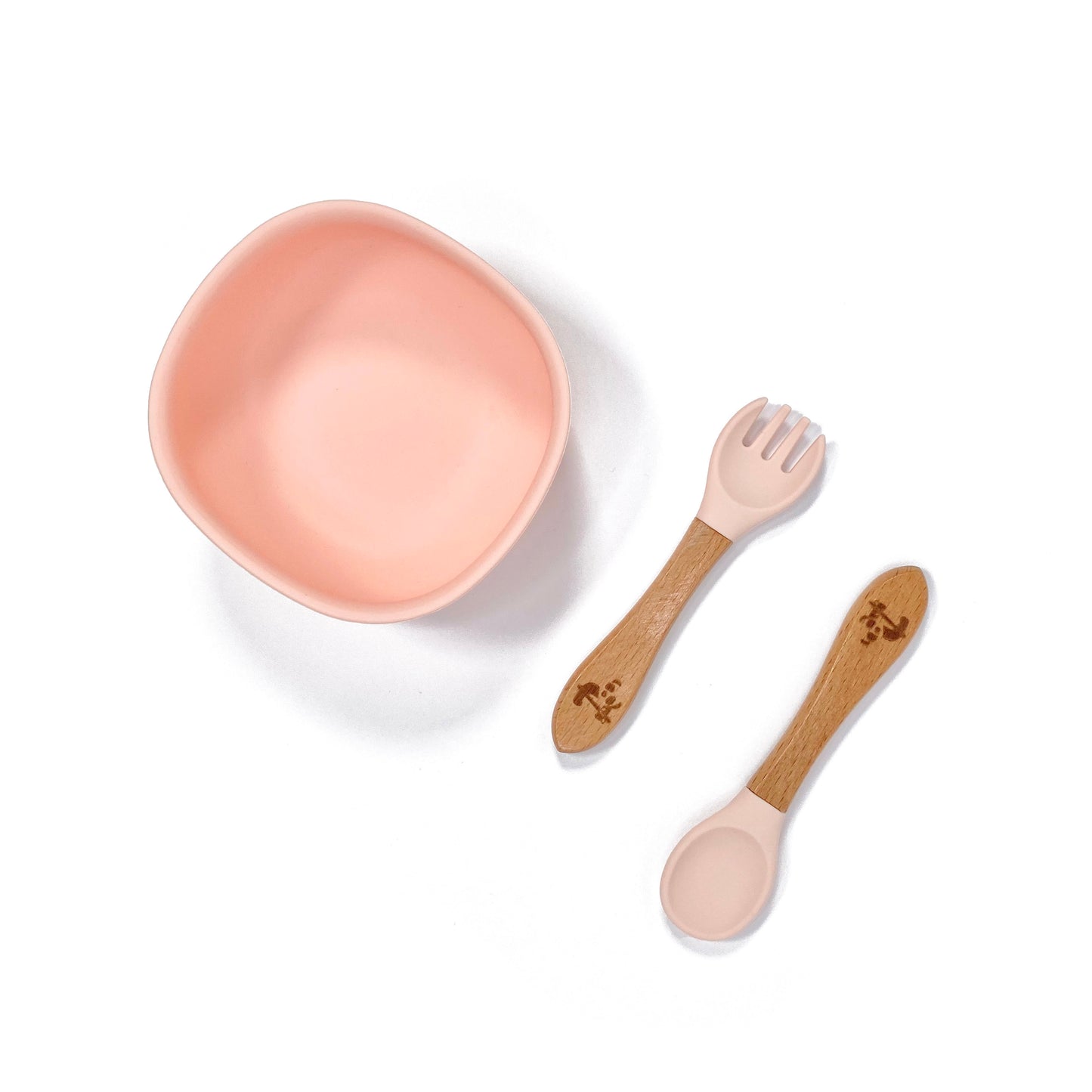 A peachy pink silicone children’s feeding bowl, with matching bamboo and silicone cutlery.
