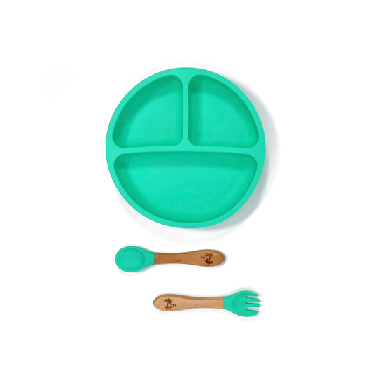 A seafoam green silicone children’s section plate with cups on the base, and matching bamboo and silicone cutlery.