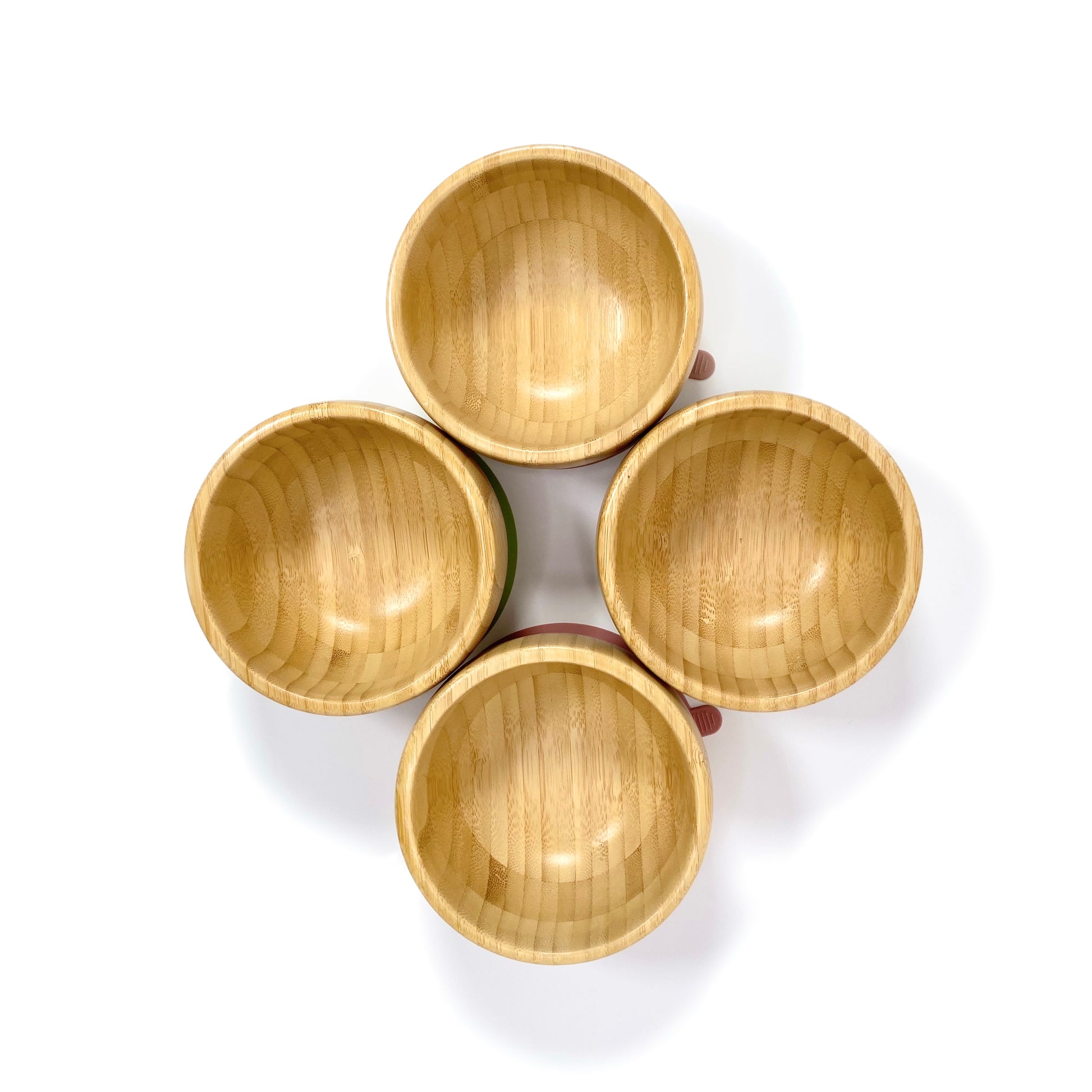 Four children’s bamboo bowls with silicone suction rings, available in four different ring colours: blossom pink, olive green, blush pink and sky blue. Image shows the four bamboo bowls from above. 