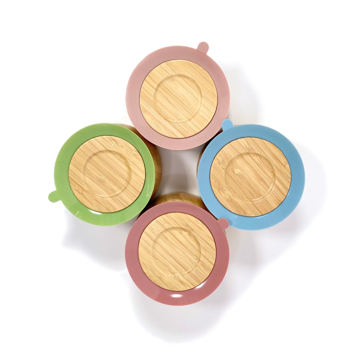 Four children’s bamboo bowls with silicone suction rings, available in four different ring colours: blossom pink, olive green, blush pink and sky blue. Image shows the underside of the bowls, featuring the silicone suction rings.