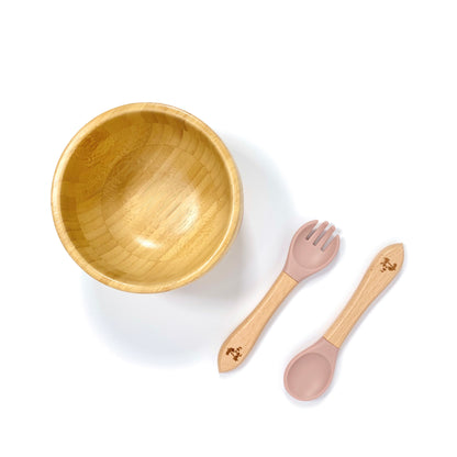 A children’s bamboo bowl with a blossom pink silicone suction ring, and matching blossom pink silicone and bamboo cutlery.