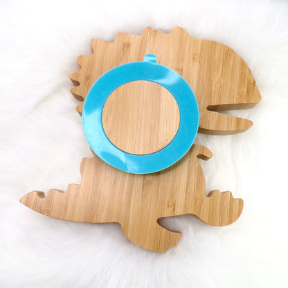 A children's bamboo section plate with a dinosaur design, blue silicone suction ring and matching blue bamboo and silicone cutlery. Back view.