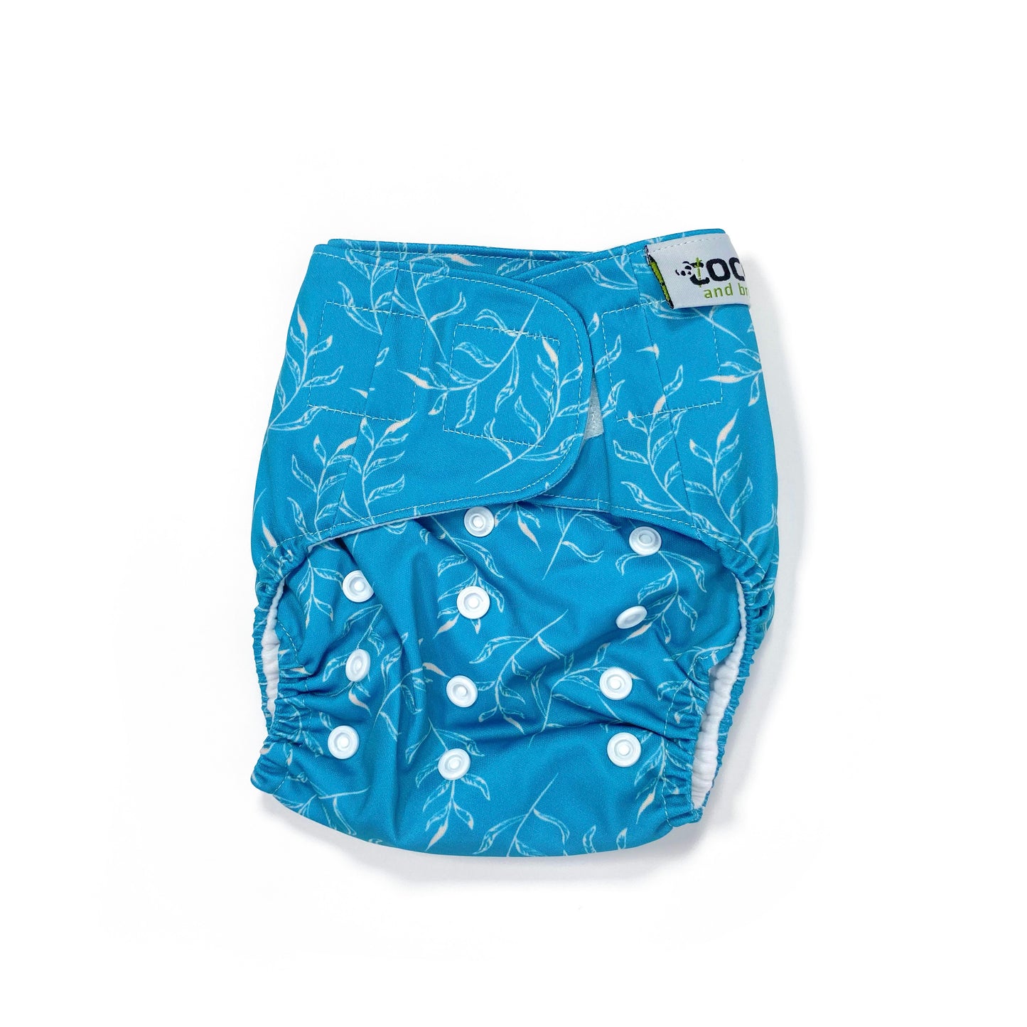 An adjustable reusable nappy for babies and toddlers, featuring a blue fern design, with images of white fern leaves on a blue background. View shows the front of the nappy, with fastenings closed.