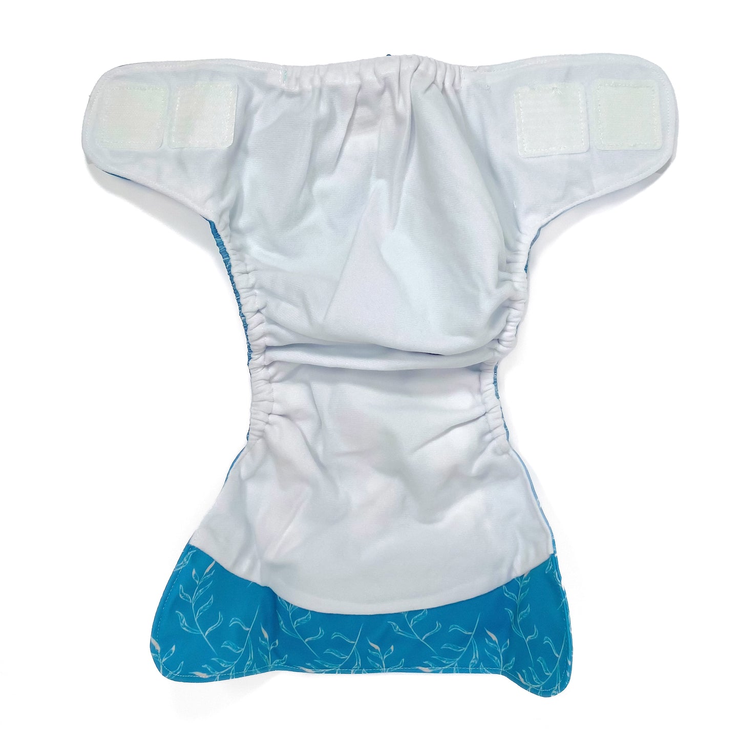 An adjustable reusable nappy for babies and toddlers, featuring a blue fern design, with images of white fern leaves on a blue background. View shows the inside fabric of the nappy.