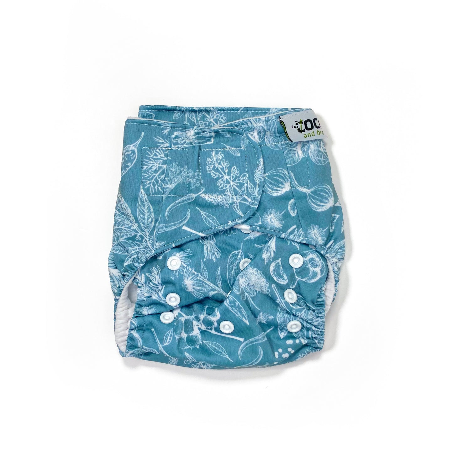 An adjustable reusable nappy for babies and toddlers, featuring a blue harvest design, with white images of various crops on a blue background.  View shows the front of the nappy, with fastenings closed.
