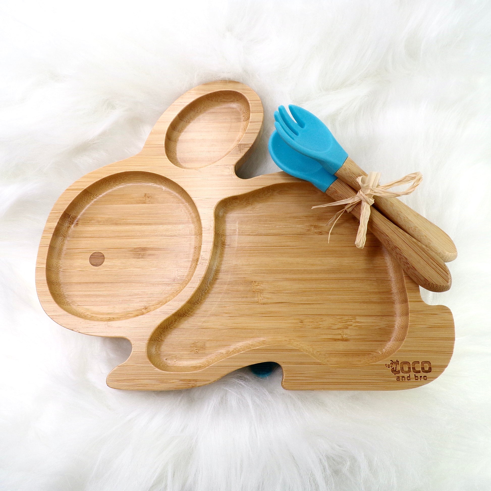 A children's bamboo section plate with a rabbit design, blue colour silicone suction ring and matching blue bamboo and silicone cutlery. Front view.