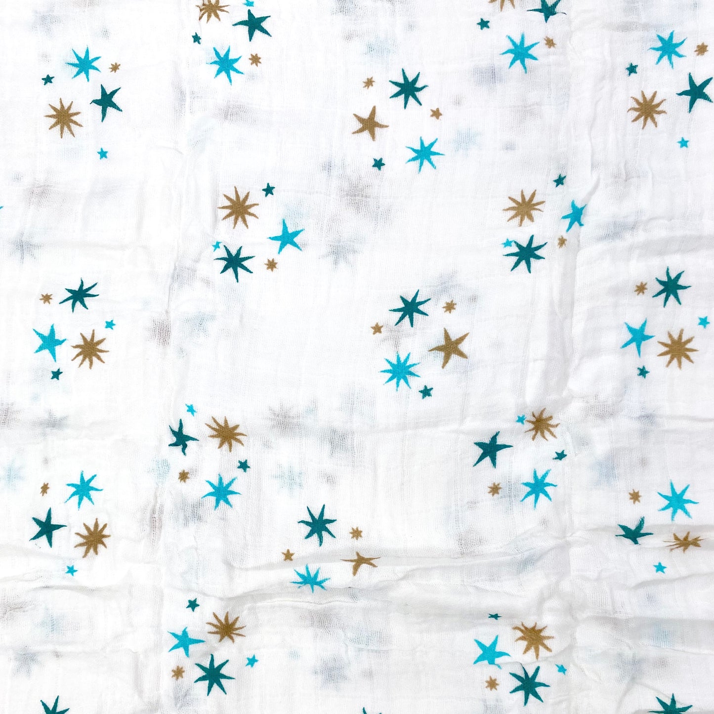 Close up pattern of a muslin swaddle blanket with a blue stars design.