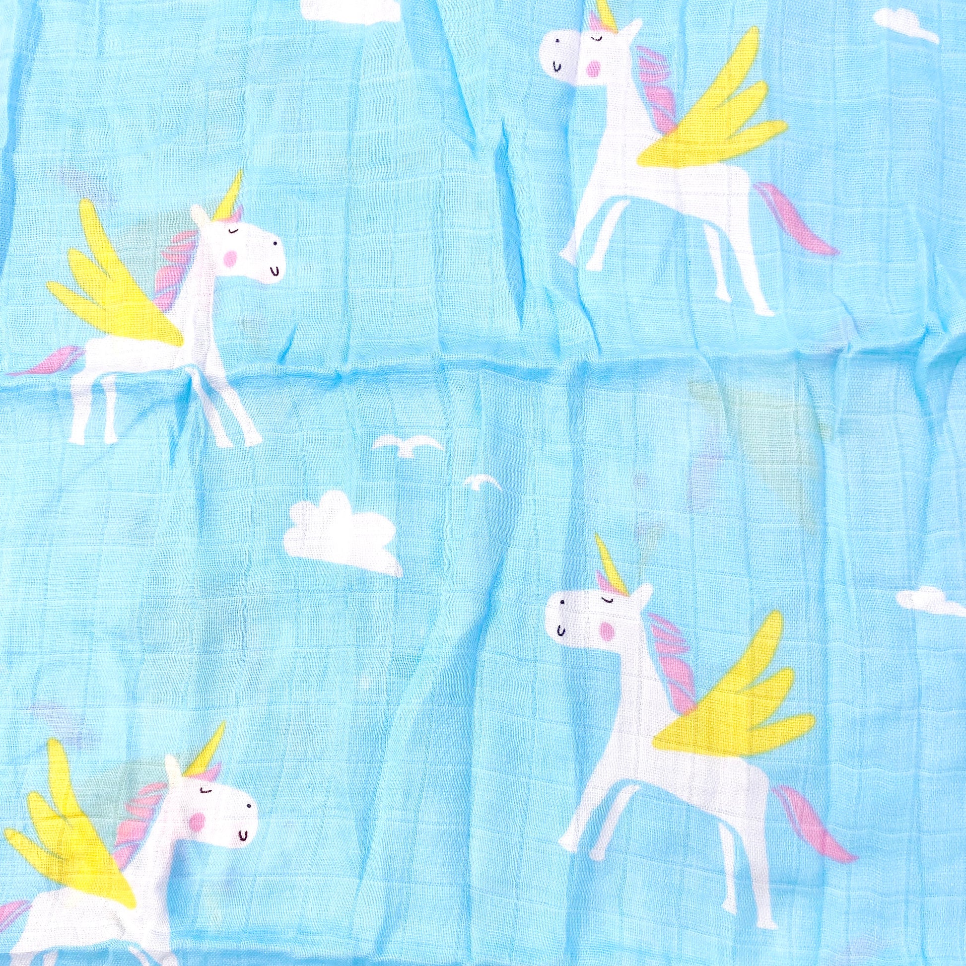 Close up pattern of a blue muslin swaddle blanket with a unicorn design.