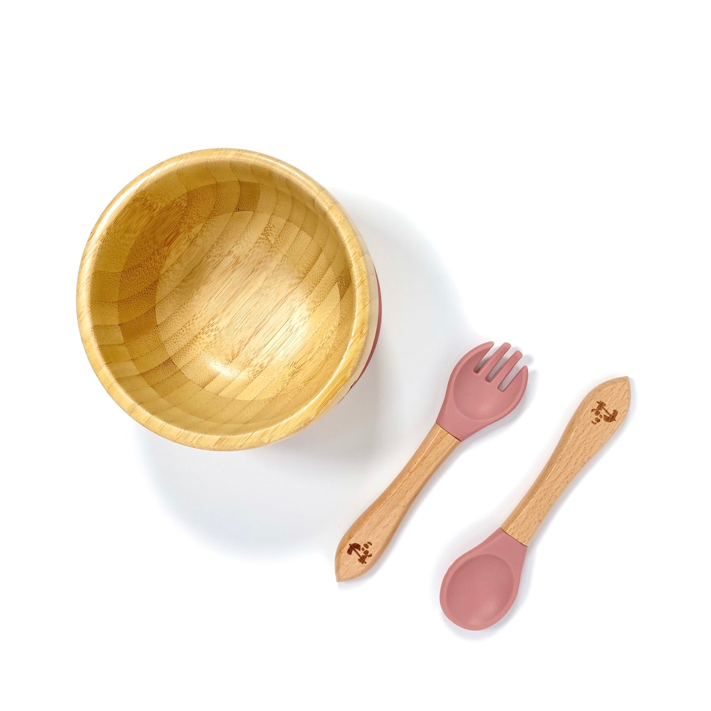 A children’s bamboo bowl with a blush pink silicone suction ring, and matching blush pink silicone and bamboo cutlery.
