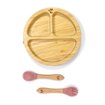 A children’s bamboo tableware set, including bamboo section plate with blush pink silicone suction ring, and matching bamboo and silicone cutlery.
