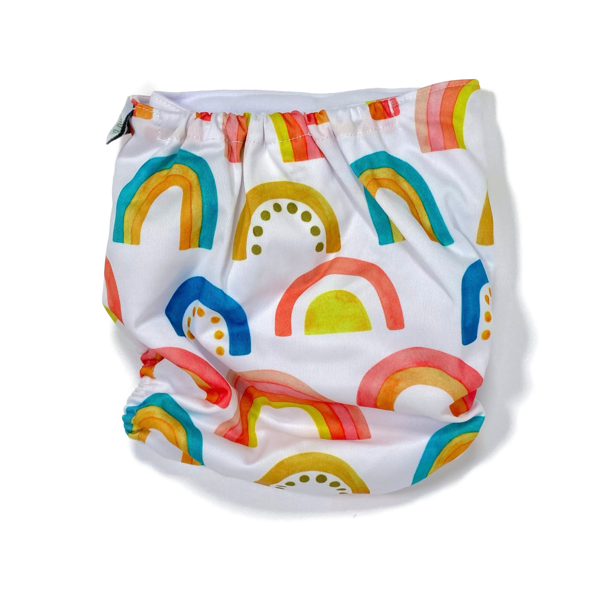 An adjustable reusable nappy for babies and toddlers, featuring a bright rainbow design, with brightly coloured rainbows on a white background. View shows the back of the nappy. 