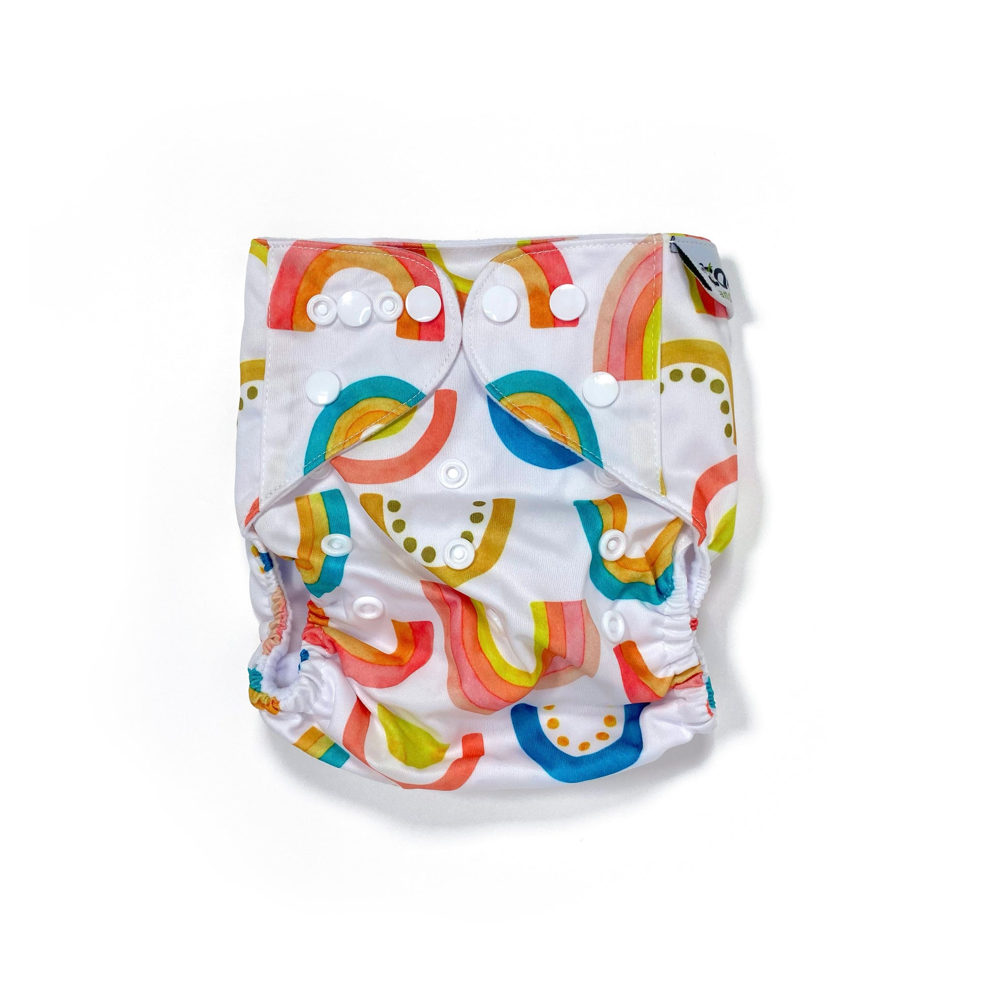 An adjustable reusable nappy for babies and toddlers, featuring a bright rainbow design, with brightly coloured rainbows on a white background. View shows the front of the nappy, with fastenings closed.