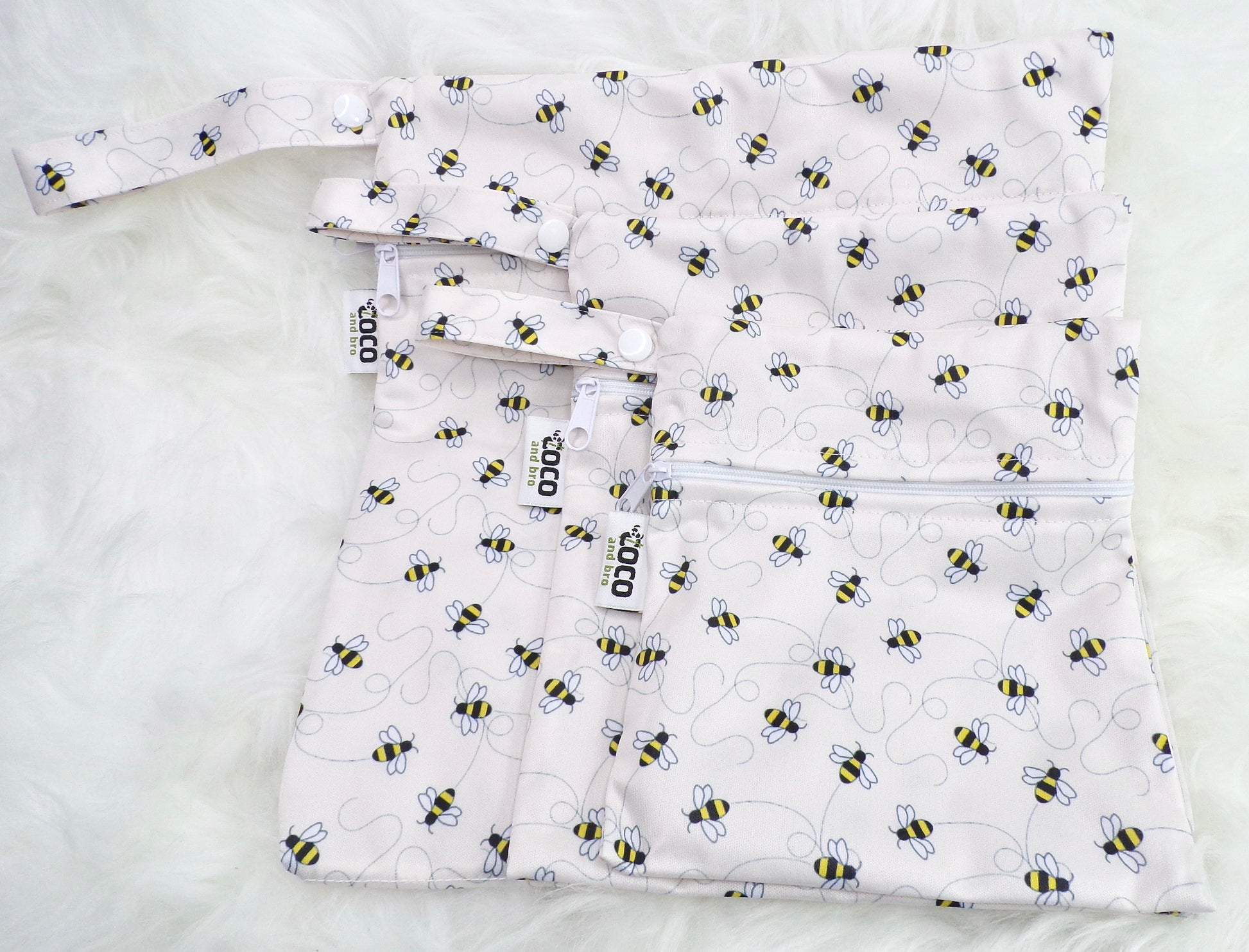 A set of three waterproof bags in an off-white bumble bee design, made from bamboo and in three different sizes. Each bag has a zipper closure.
