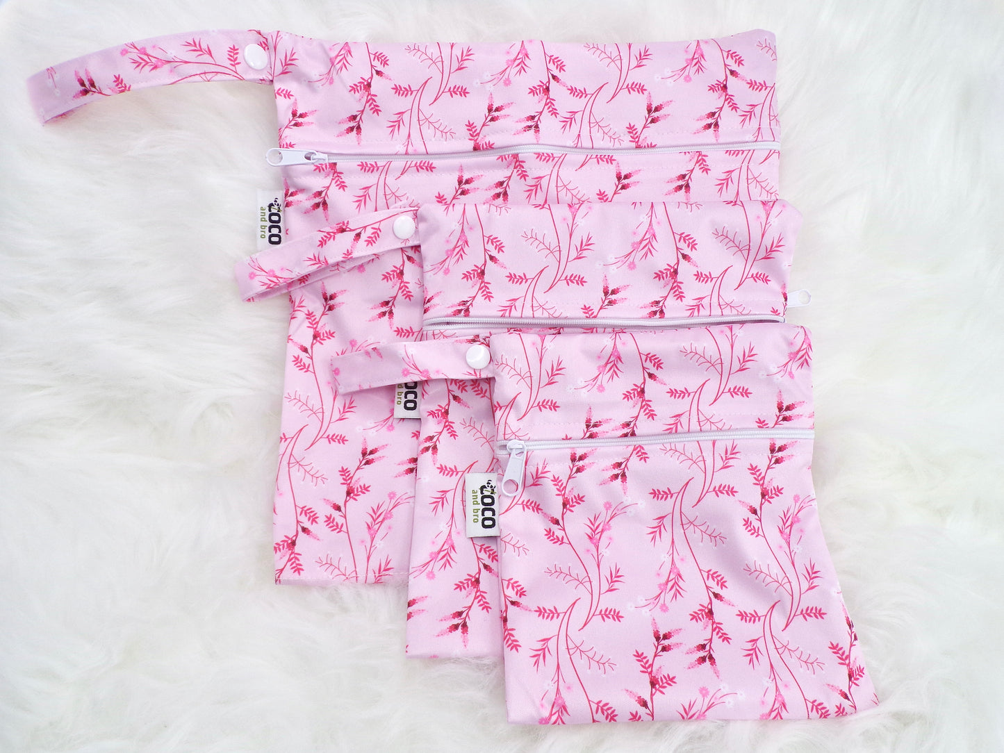 A set of three waterproof bags in a pink floral design, made from bamboo and in three different sizes. Each bag has a zipper closure.