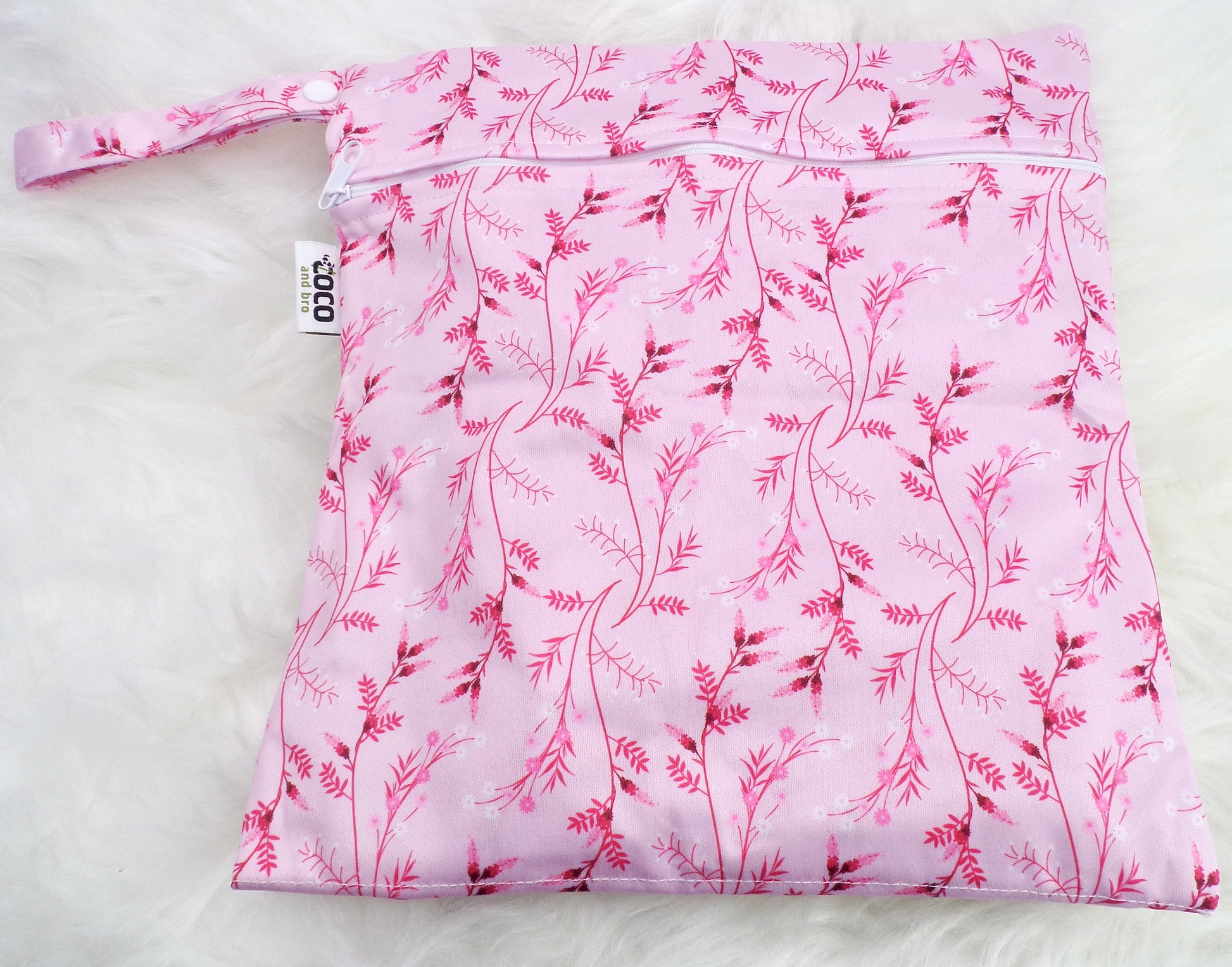 A set of three waterproof bags in a pink floral design, made from bamboo and in three different sizes. Each bag has a zipper closure. Image shown displays the largest bag with the two smaller bags contained within.