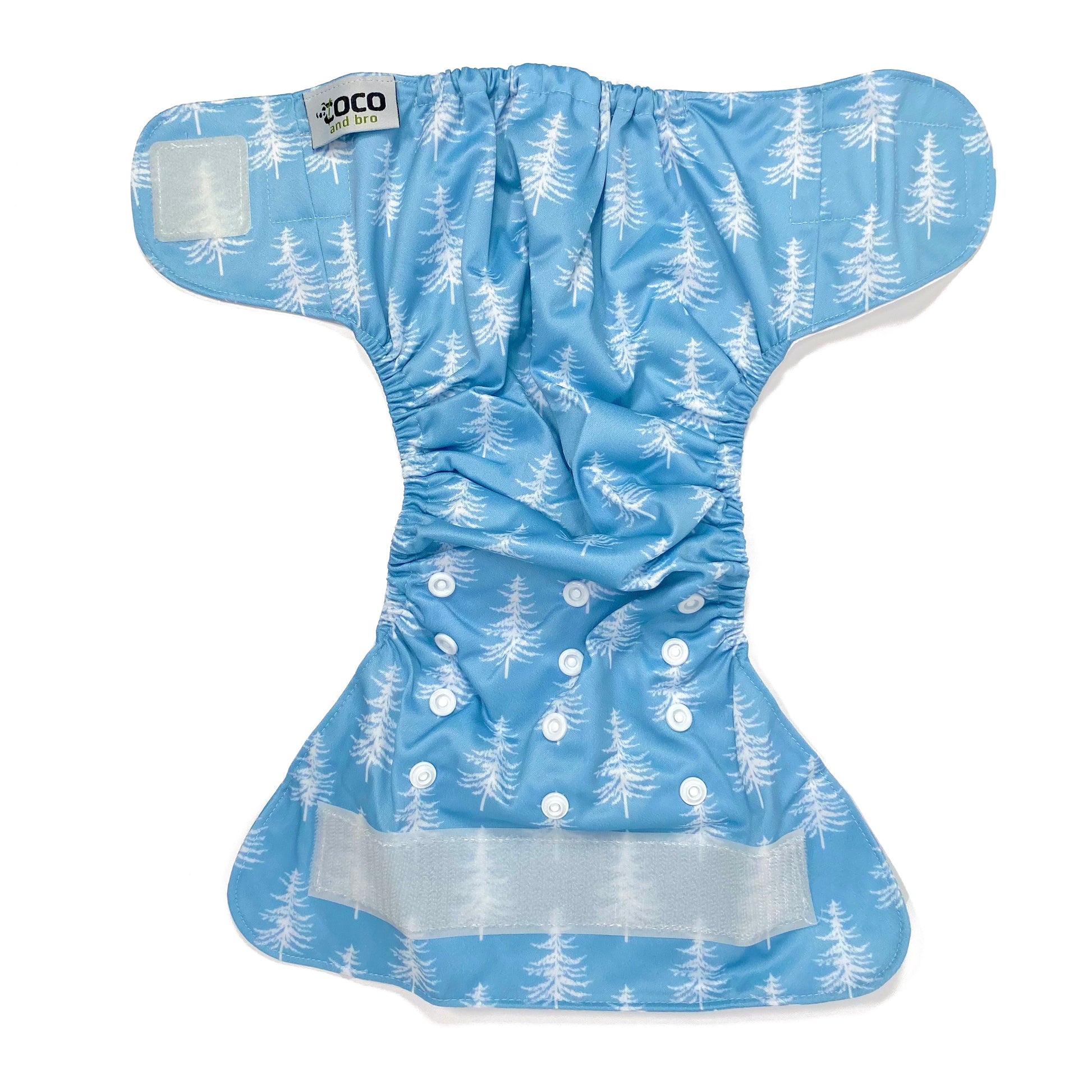 An adjustable reusable nappy for babies and toddlers, featuring a cool blue pine design design, with images of white pine trees on a blue background. View shows the full outside pattern of the nappy, with fastenings open.