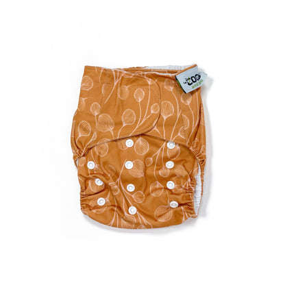An adjustable reusable nappy for babies and toddlers, featuring a floral copper design, with floral images on a copper background. View shows the front of the nappy.