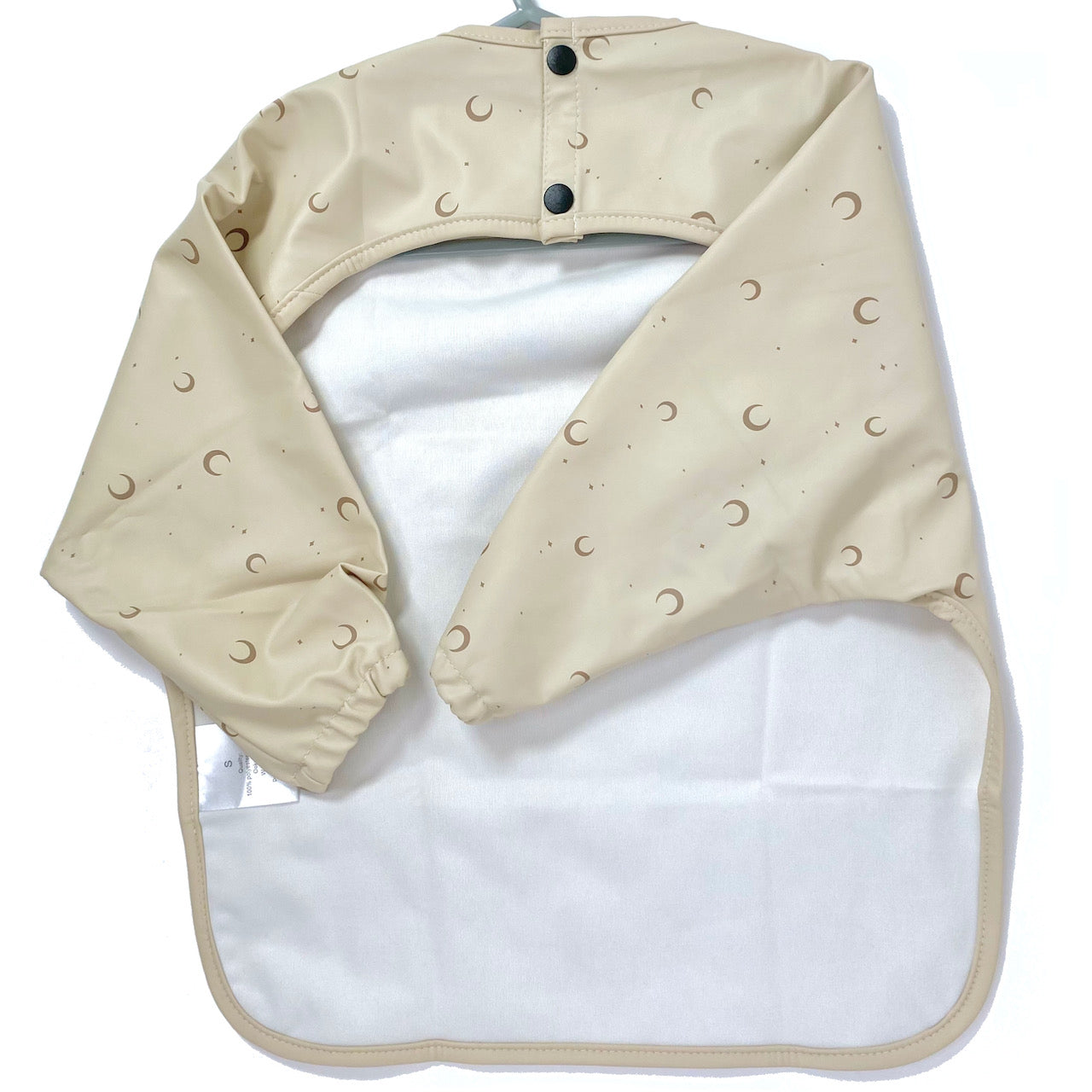 Long-sleeve kids apron in a beige and moon design, showing back view.