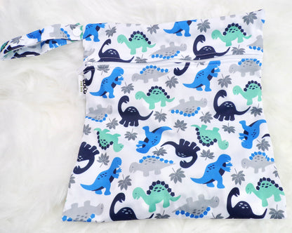 A set of three waterproof bags in a green and blue dinosaur design on a white background, made from bamboo and in three different sizes. Each bag has a zipper closure.  Image shown displays the largest bag with the two smaller bags contained within.