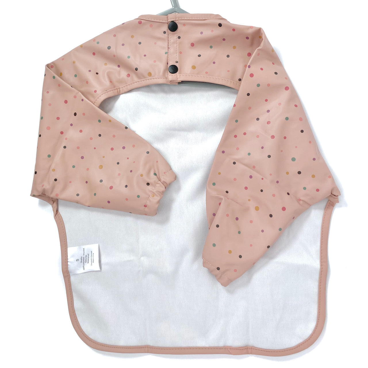 Long-sleeve kids apron in a rose pink and dotty design, showing back view.