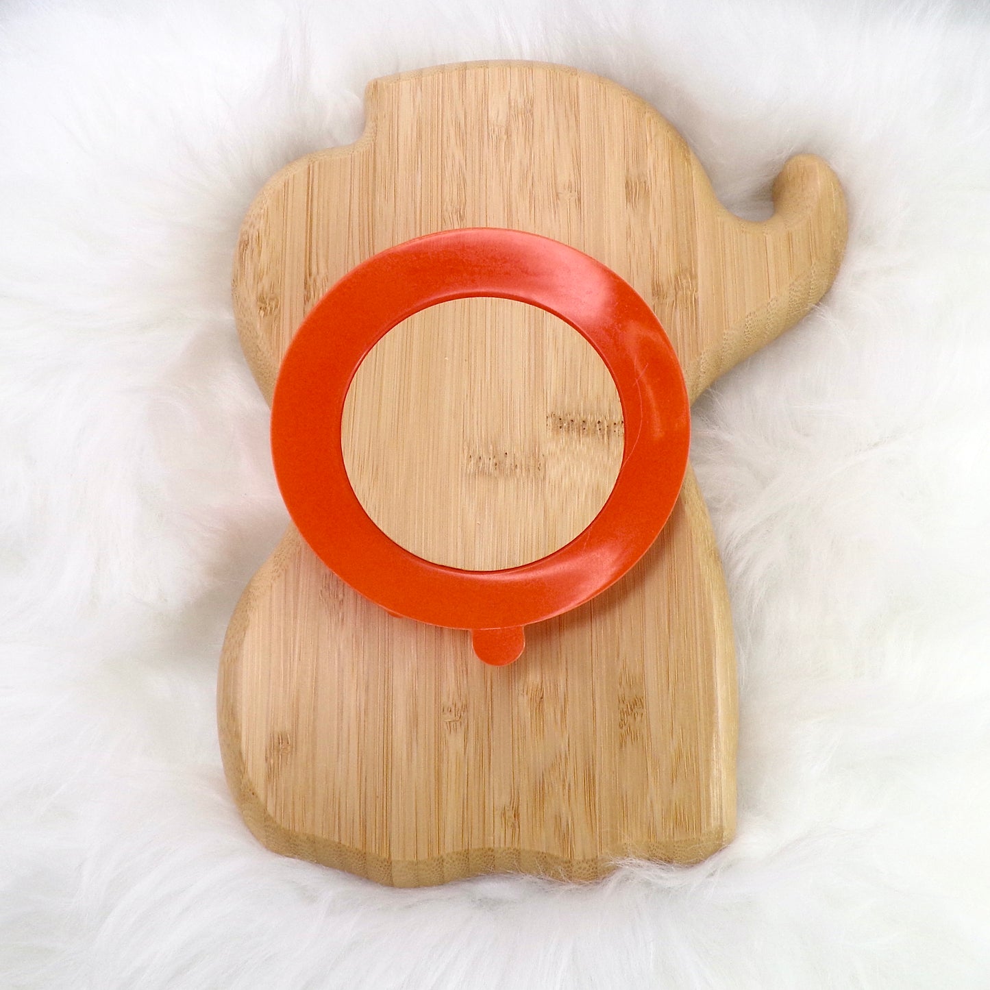 A children's bamboo section plate with an elephant design, orange colour silicone suction ring and matching orange bamboo and silicone cutlery. Back view.