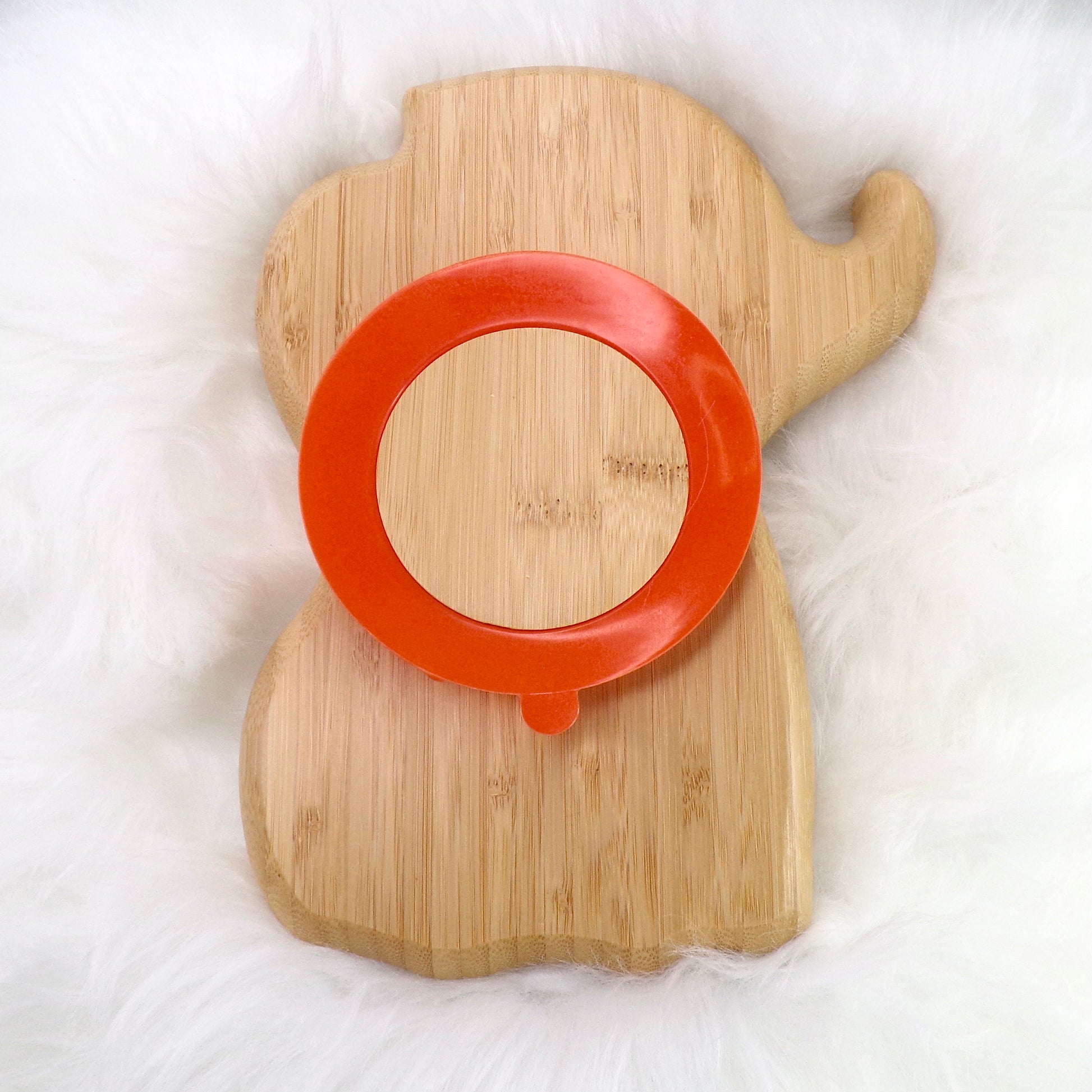 A children's bamboo section plate with an elephant design, orange colour silicone suction ring and matching orange bamboo and silicone cutlery. Back view.