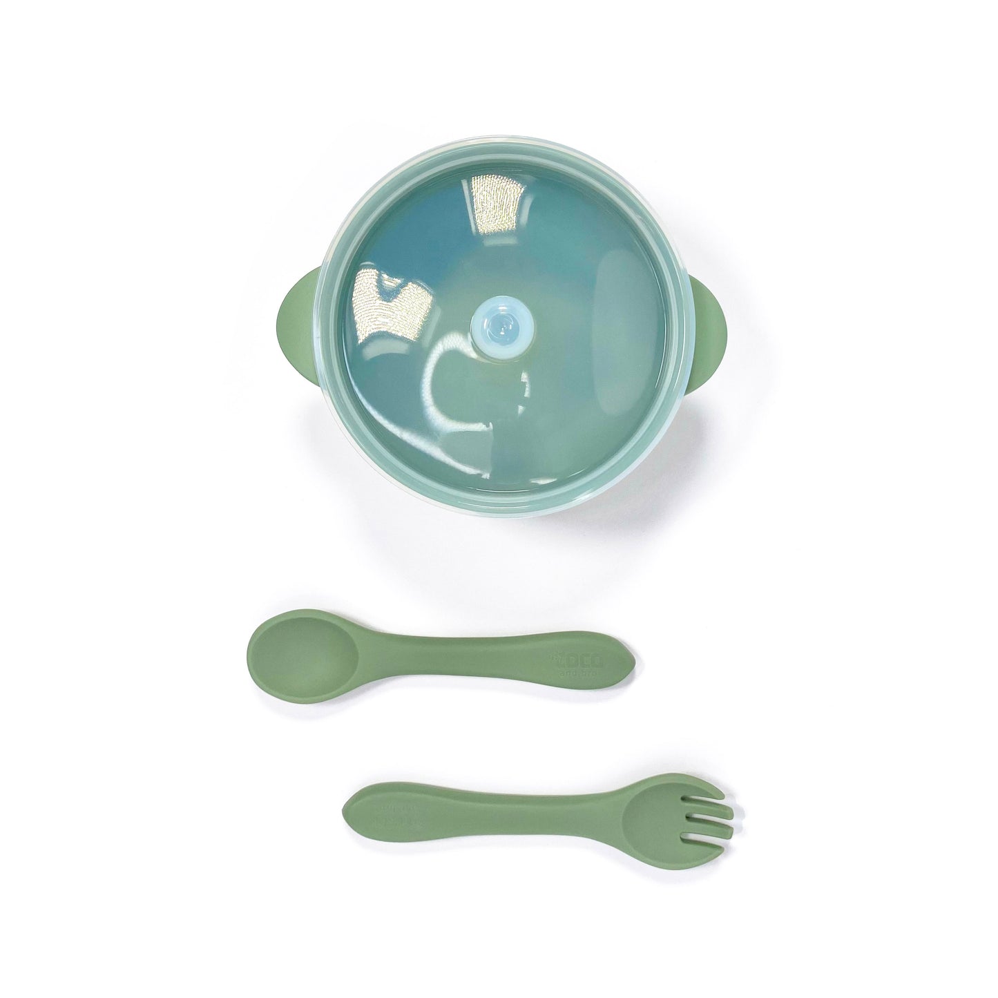 A forest green silicone children’s feeding set, including silicone bowl with lid and matching silicone cutlery. Image shows the bowl and cutlery from above, with lid attached.