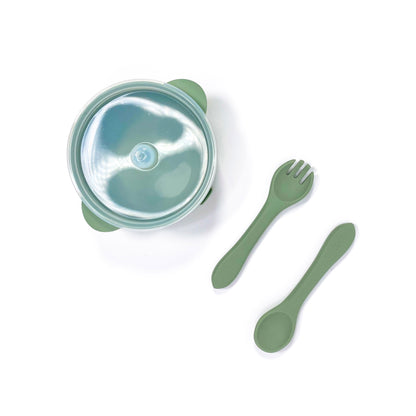 A forest green silicone children’s feeding set, including silicone bowl with lid and matching silicone cutlery. Image shows the bowl and cutlery from above, with lid attached.