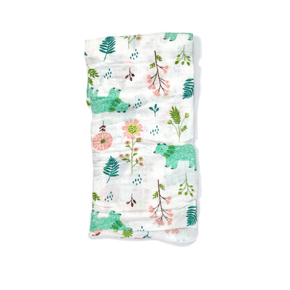 A folded muslin swaddle blanket with a green bear design.
