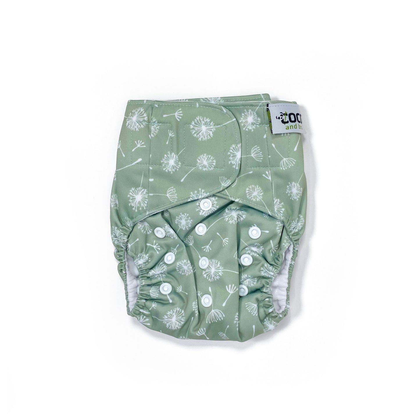 An adjustable reusable nappy for babies and toddlers, featuring a green dandelion design, with images of dandelion seeds on a green background. View shows the front of the nappy.