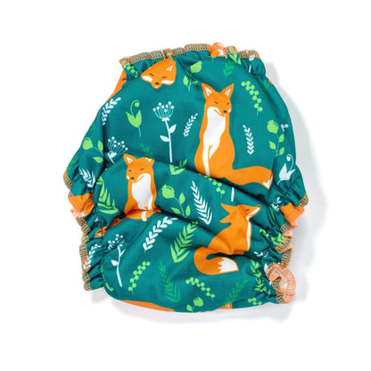 An adjustable reusable nappy for babies and toddlers, featuring a green fox design, with images of foxes on a green background. View shows the back of the nappy.