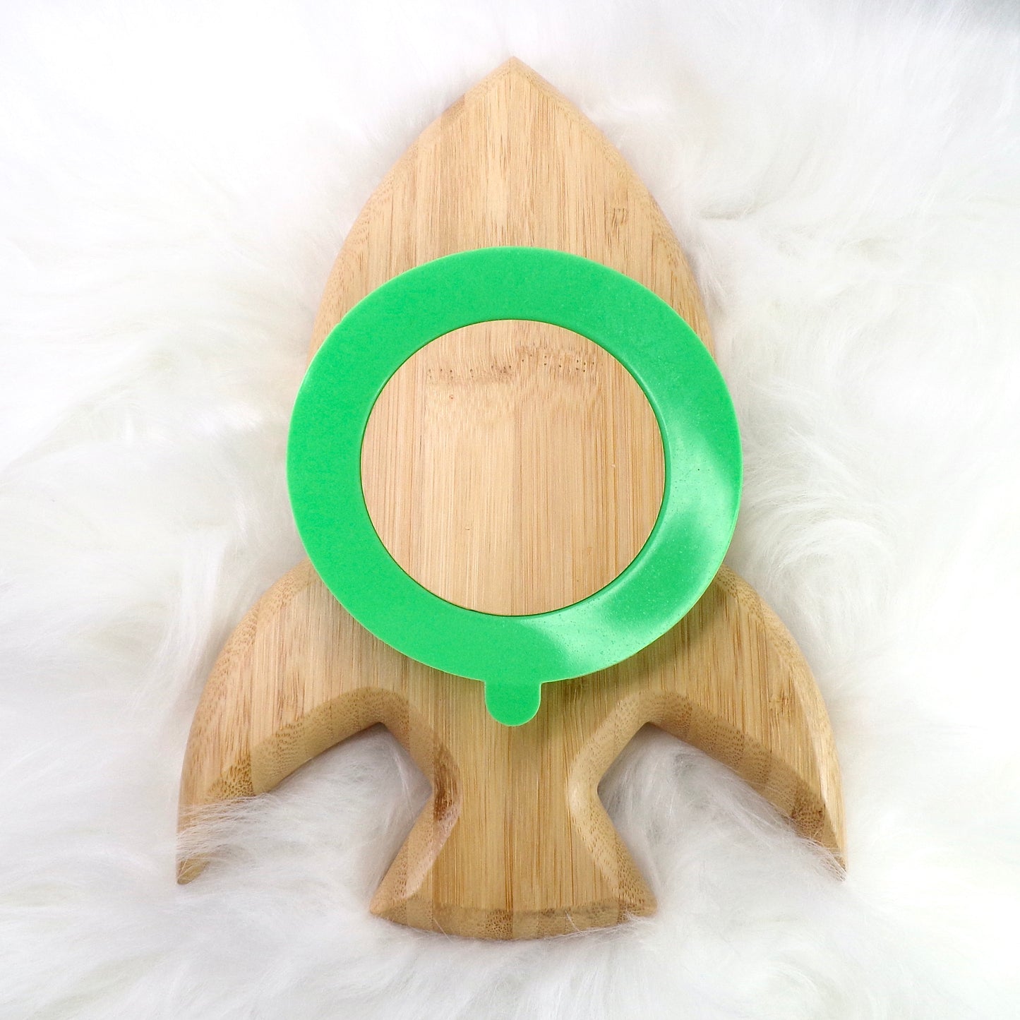 A children's bamboo section plate with a rocket design, green colour silicone suction ring and matching green bamboo and silicone cutlery. Back view.