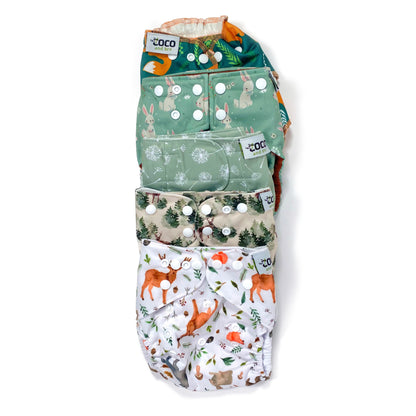 A set of five reusable nappies, made from 100% recycled polyester. The included nappies are: Woodland Friends, Winter Forest, Green Dandelion, Green Rabbits and Green Fox. View shows all five nappies front facing, in a vertical line.