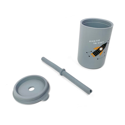 A children’s grey silicone drinking cup, with matching lid and straw, featuring a rocket design. The image shows the cup, lid and straw separately.