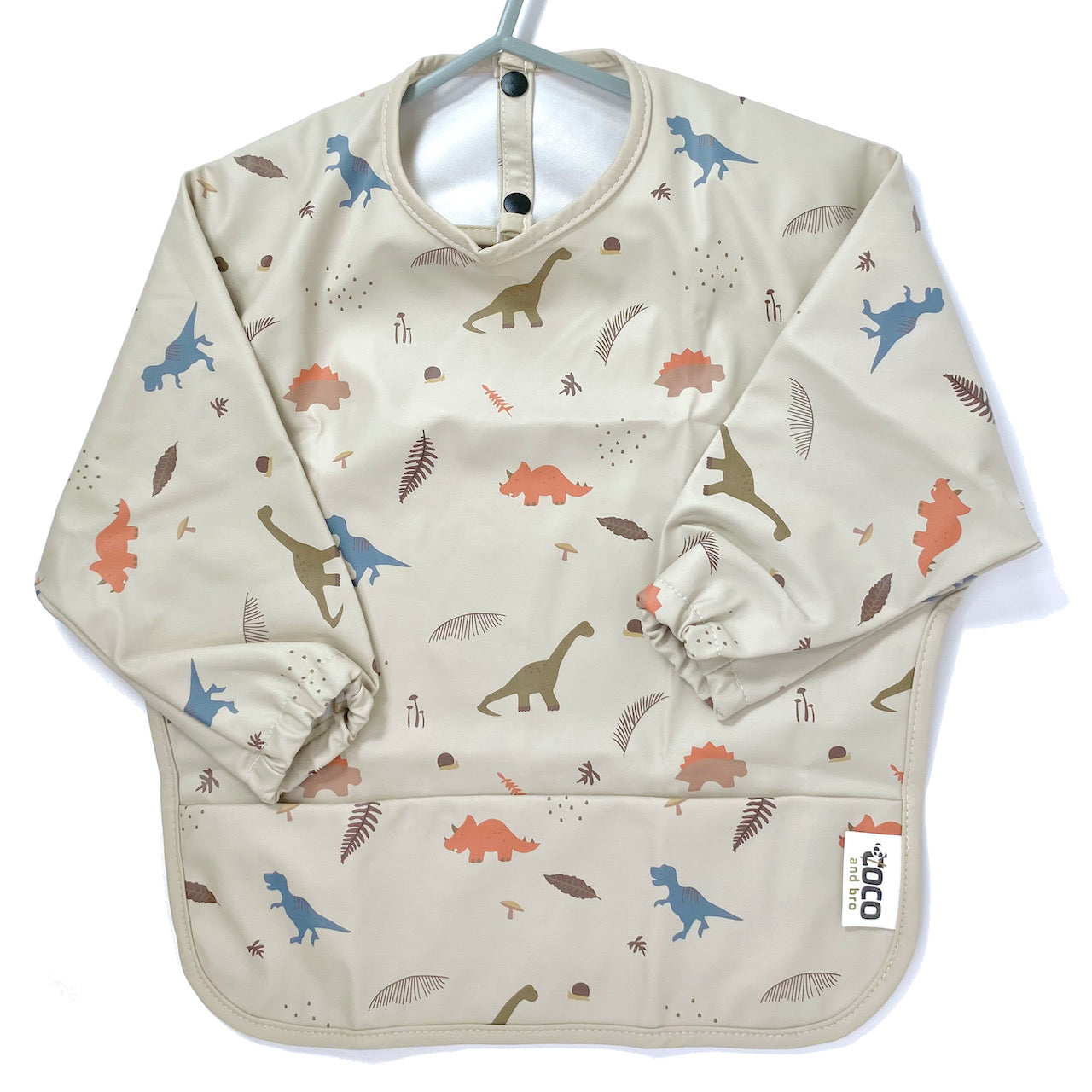 Long-sleeve kids apron in a beige and dinosaur design, showing front view.