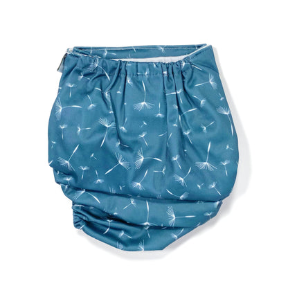 An adjustable reusable nappy for babies and toddlers, featuring a midnight breeze design, with images of dandelion seeds on a navy blue background. View shows the back of the nappy.