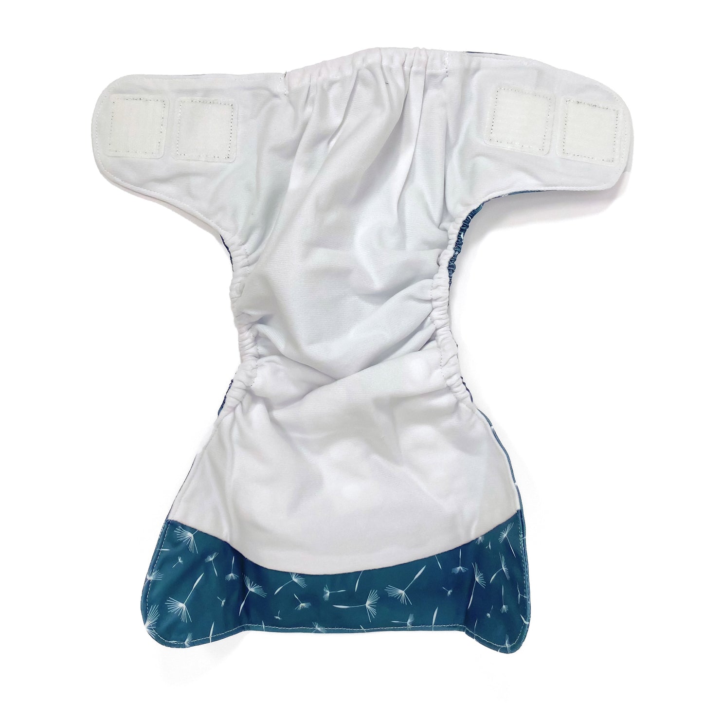 An adjustable reusable nappy for babies and toddlers, featuring a midnight breeze design, with images of dandelion seeds on a navy blue background. View shows the inside fabric of the nappy.