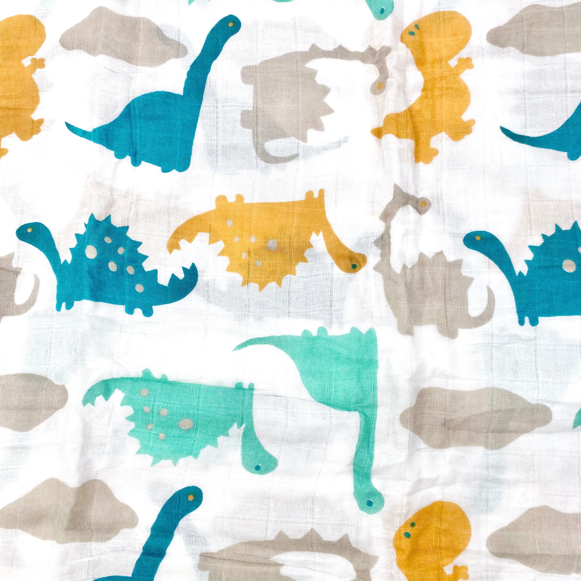 Close up pattern of a muslin swaddle blanket with a neutral dinosaur design.