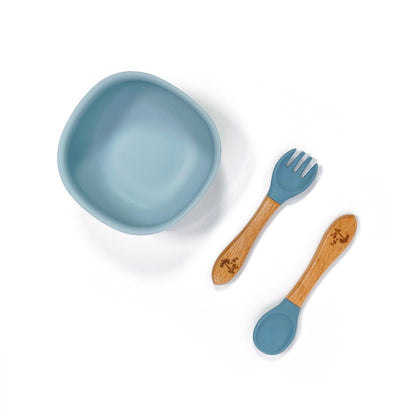An ocean blue silicone children’s feeding bowl, with matching bamboo and silicone cutlery.
