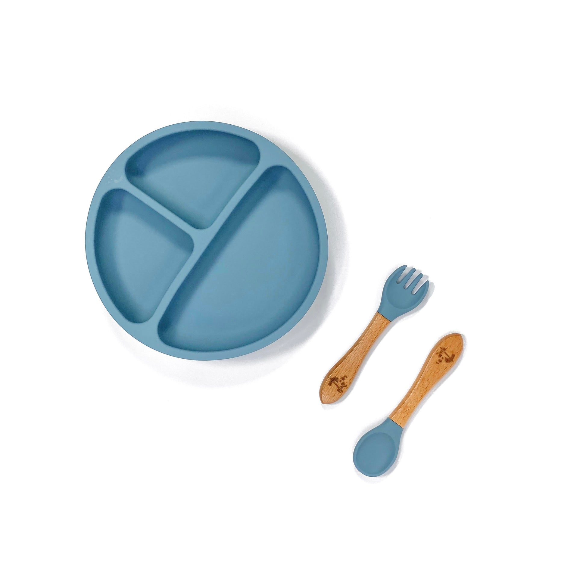 An ocean blue silicone children’s section plate with cups on the base, and matching bamboo and silicone cutlery.