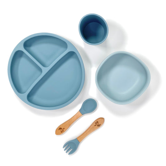 An ocean blue silicone children’s feeding set, comprised of silicone section plate with suction cups, silicone bowl with suction cup, silicone drinking cup and matching bamboo and silicone cutlery.