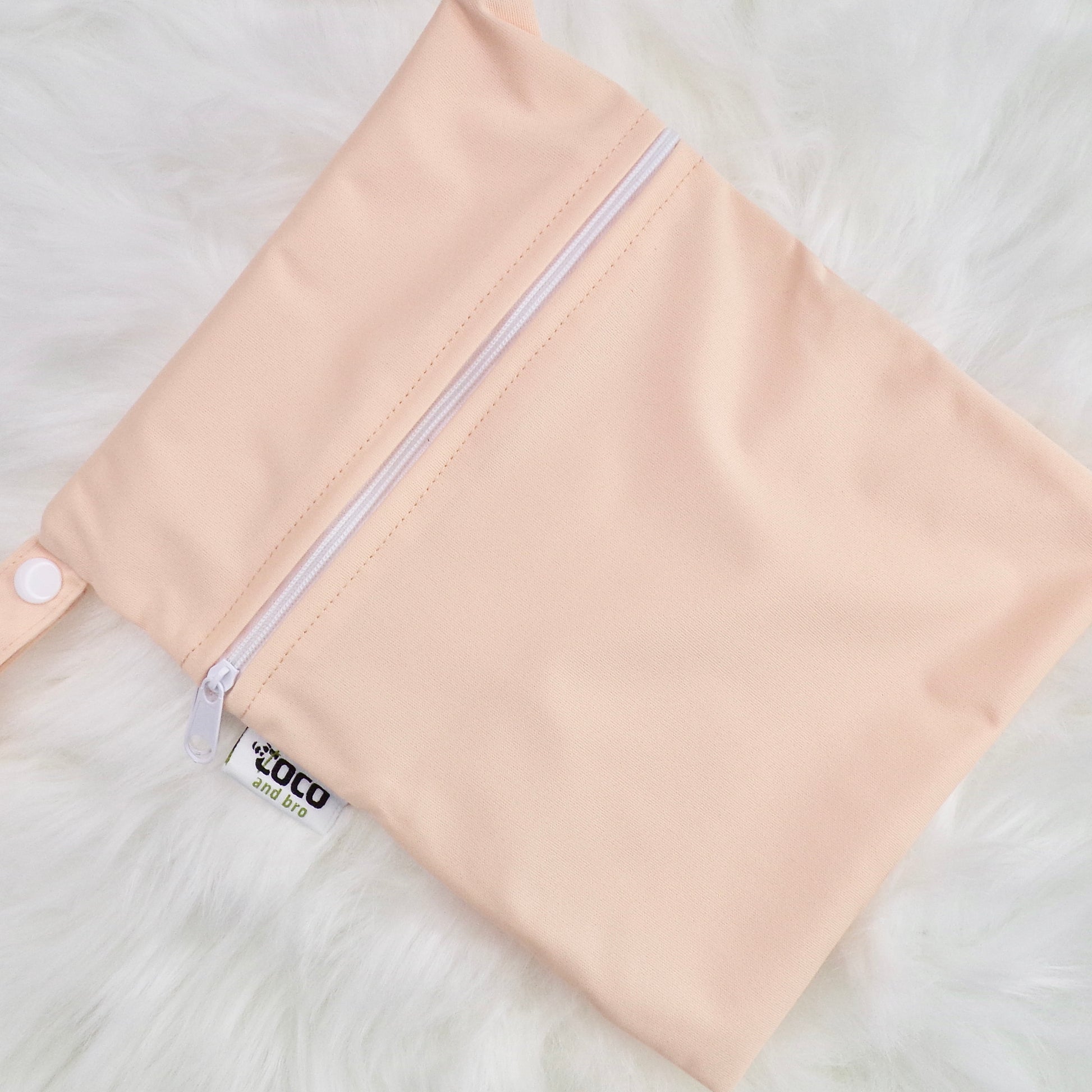 Each backpack purchase includes a free waterproof bag. This image shows the waterproof bag in peachy pink, with a zip closure.