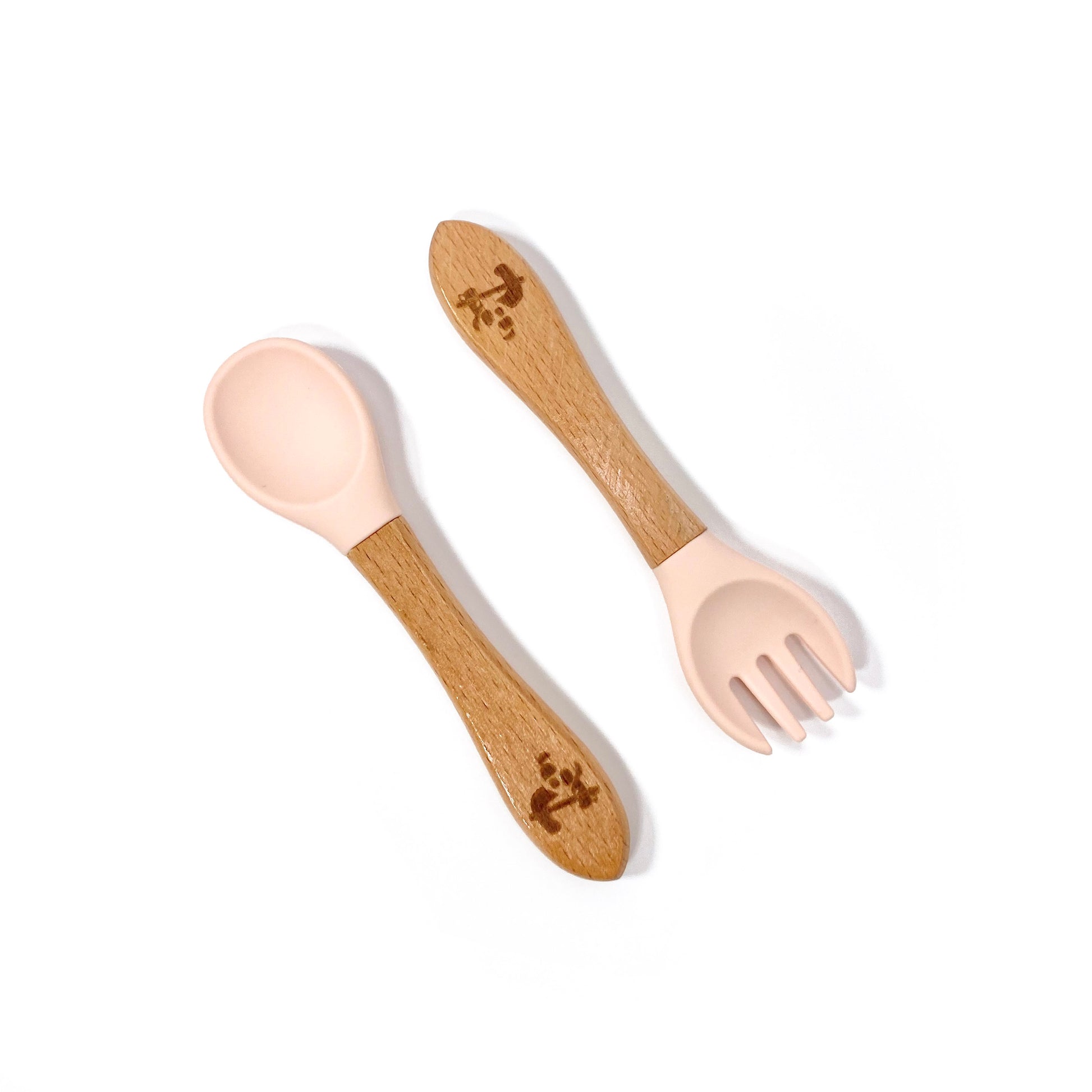 A set of children’s bamboo and silicone cutlery, in peachy pink. The set is comprised of a fork and spoon.