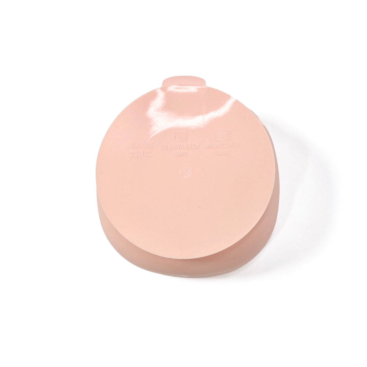 A peachy pink silicone children’s feeding bowl with suction cup on the base. View shows the underside of the bowl.